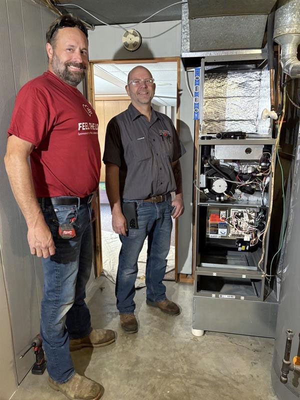 Two techs standing next to a newly installed furnace
